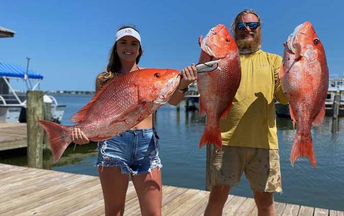 man and woman holding fish on a pier