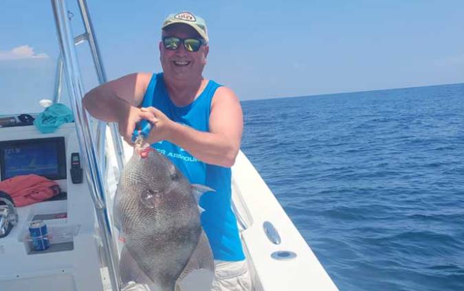 man in blue tank-top holding a fish