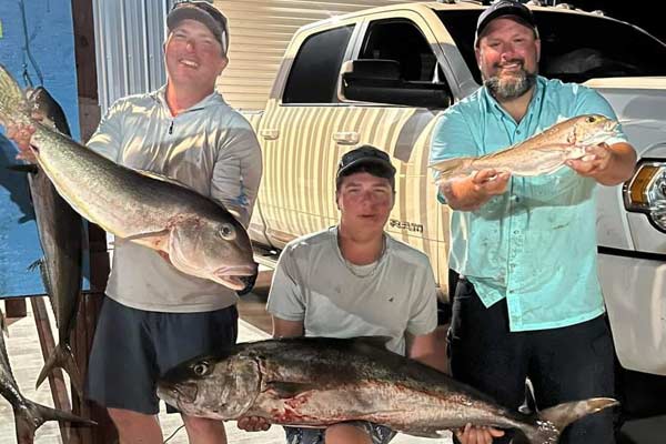 three men holding fish